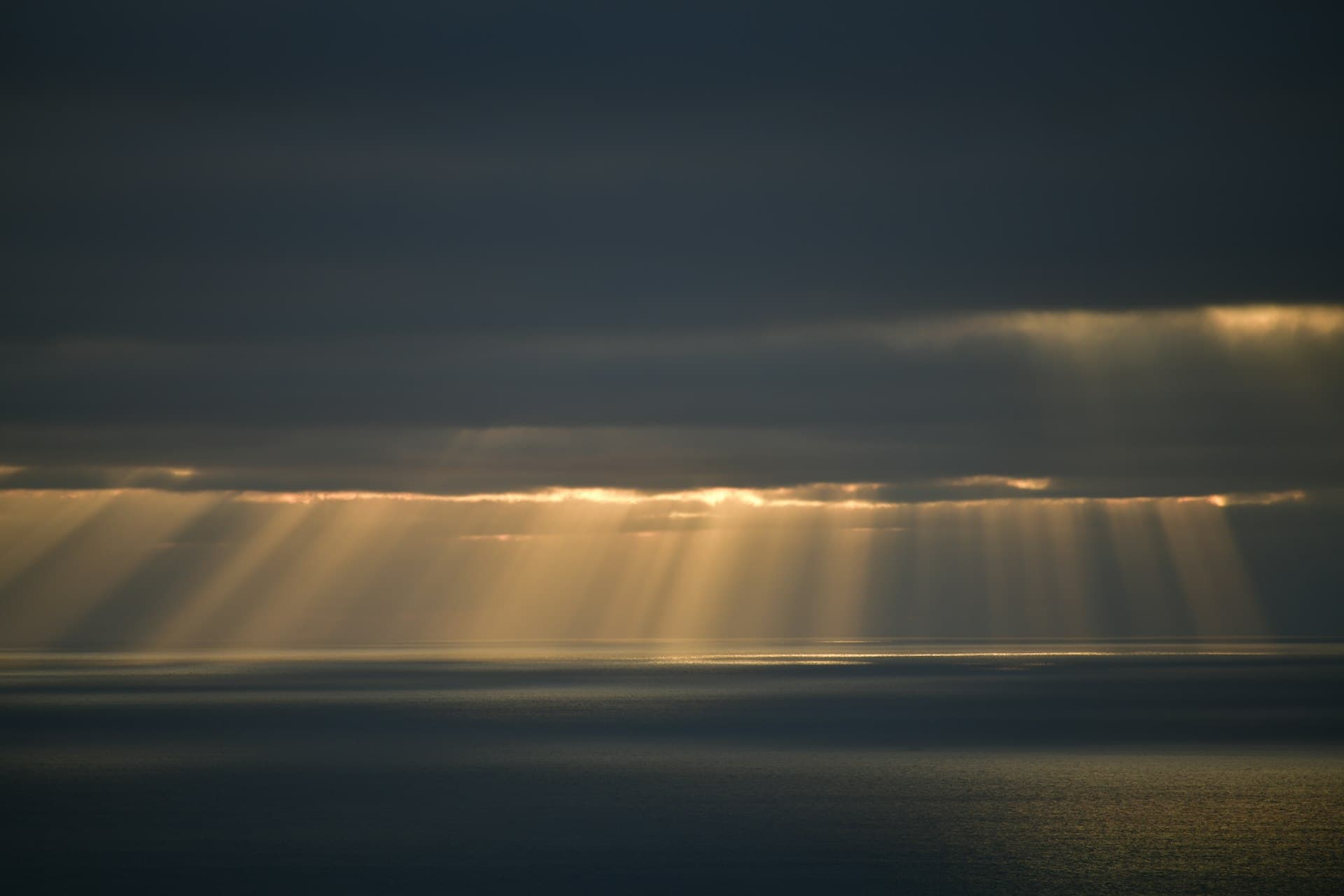 Sunlight streaming through dark clouds over the ocean
